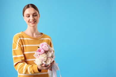 Photo of Woman with beautiful bouquet of peonies on light blue background, space for text