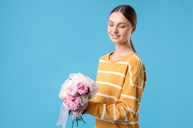 Photo of Woman with beautiful bouquet of peonies on light blue background, space for text