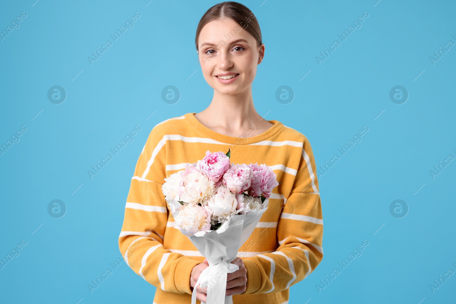 Woman with beautiful bouquet of peonies on light blue background Photo of Woman with beautiful bouquet of peonies on light blue background