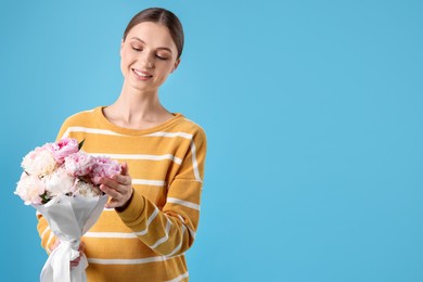 Photo of Woman with beautiful bouquet of peonies on light blue background, space for text