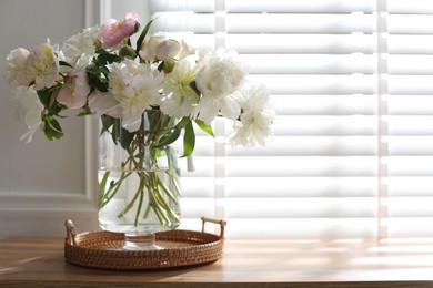 Photo of Vase with beautiful flowers near window on wooden table, space for text