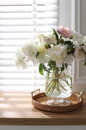 Photo of Vase with beautiful flowers near window on wooden table