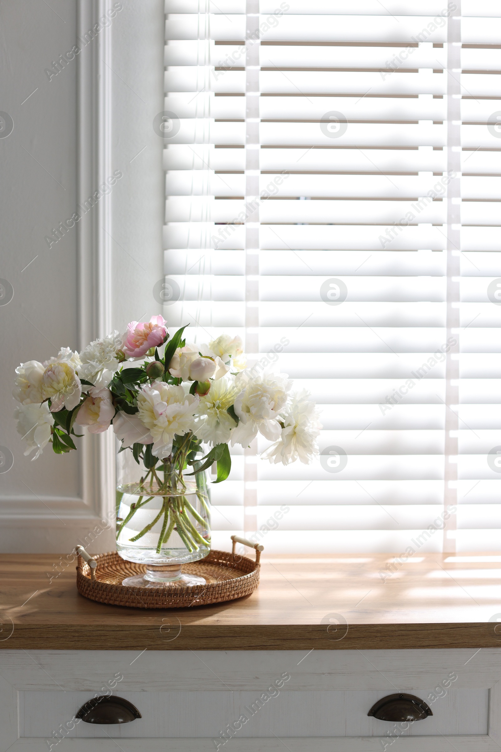 Vase with beautiful flowers near window on wooden table, space for text Photo of Vase with beautiful flowers near window on wooden table, space for text