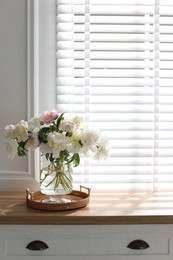 Photo of Vase with beautiful flowers near window on wooden table, space for text
