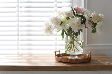 Photo of Vase with beautiful flowers near window on wooden table, space for text