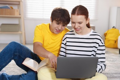 Photo of Teenage students with laptop studying on floor at home