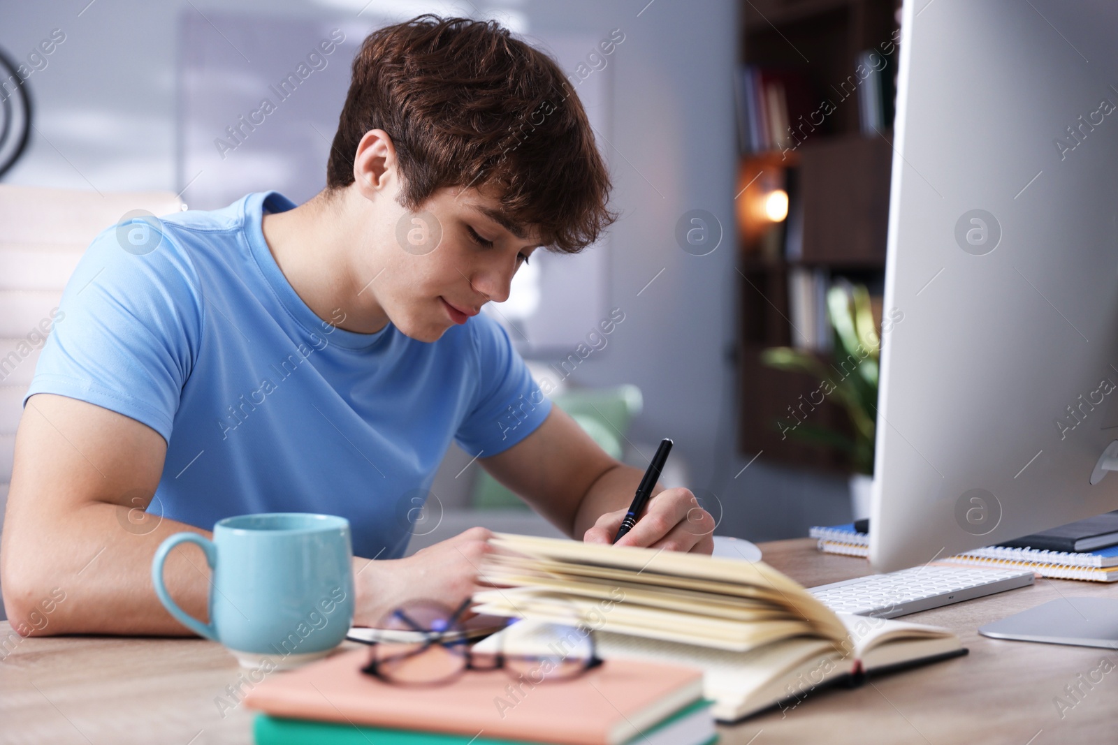 Teenage student taking notes while studying at table indoors Photo of Teenage student taking notes while studying at table indoors