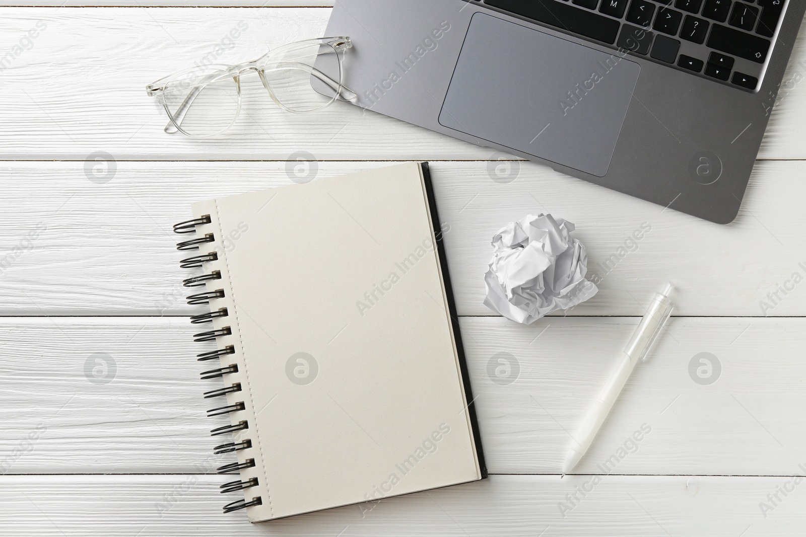 Notebook, pen, glasses, laptop and crumpled paper on white wooden table, flat lay Photo of Notebook, pen, glasses, laptop and crumpled paper on white wooden table, flat lay