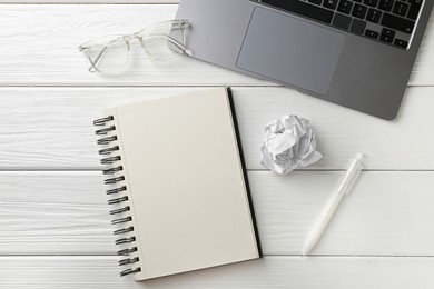 Photo of Notebook, pen, glasses, laptop and crumpled paper on white wooden table, flat lay