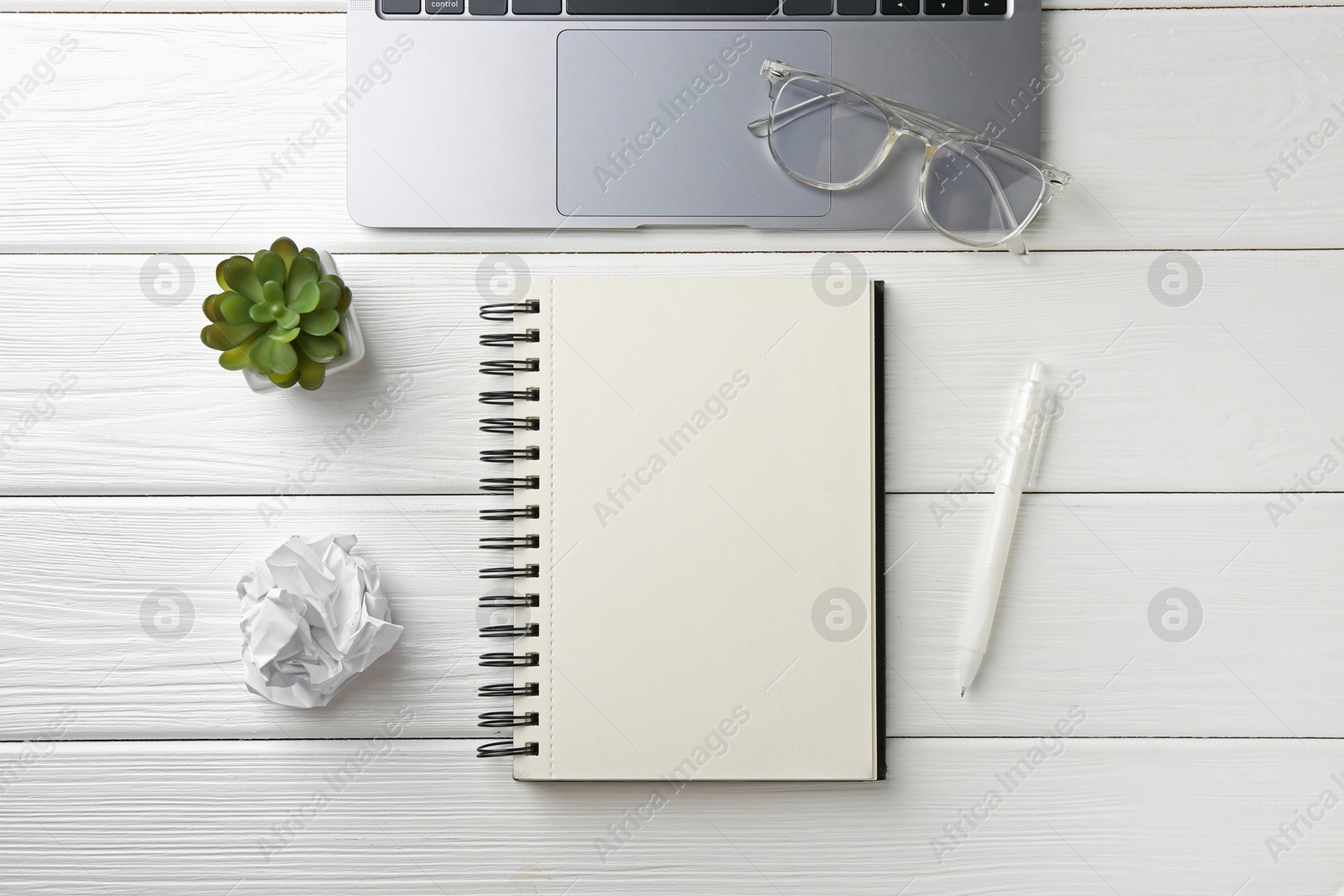 Notebook, pen, glasses, laptop, crumpled paper and floral decor on white wooden table, flat lay Photo of Notebook, pen, glasses, laptop, crumpled paper and floral decor on white wooden table, flat lay