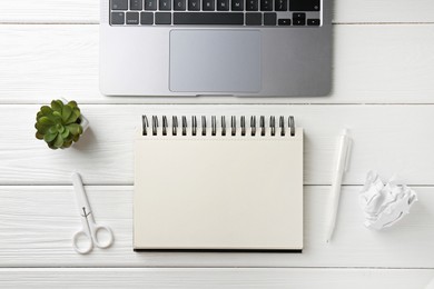 Photo of Notebook, pen, laptop, crumpled paper, scissors and floral decor on white wooden table, flat lay