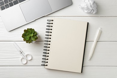Photo of Notebook, pen, laptop, crumpled paper, scissors and floral decor on white wooden table, flat lay