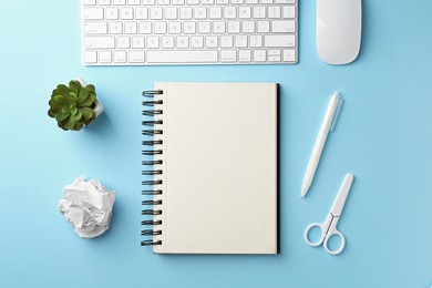 Photo of Notebook, other stationery, floral decor, computer keyboard and mouse on light blue background, flat lay