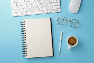 Photo of Notebook, pen, coffee, glasses, computer keyboard and mouse on light blue background, flat lay