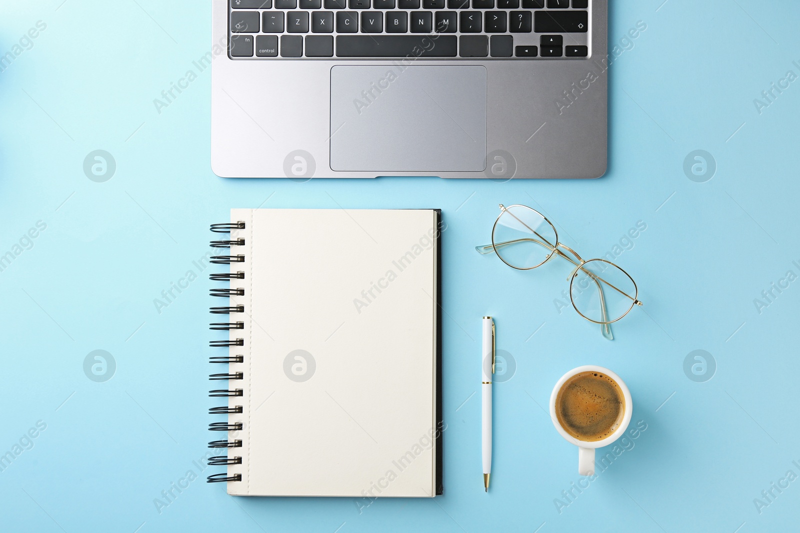 Photo of Notebook, pen, laptop, glasses and coffee on light blue background, flat lay