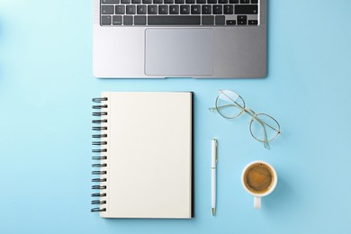 Photo of Notebook, pen, laptop, glasses and coffee on light blue background, flat lay