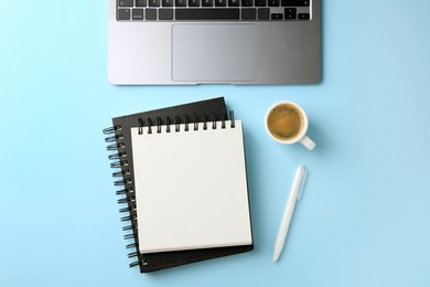 Photo of Notebooks, pen, coffee and laptop on light blue background, flat lay