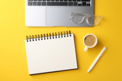 Photo of Notebook, pen, glasses and laptop on yellow background, flat lay