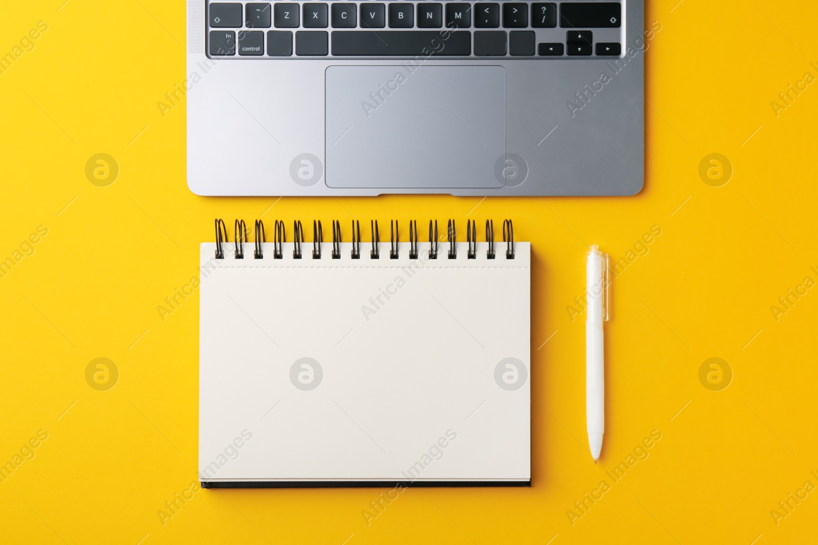 Notebook, pen and laptop on yellow background, flat lay Photo of Notebook, pen and laptop on yellow background, flat lay