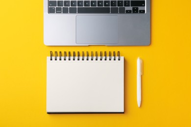 Photo of Notebook, pen and laptop on yellow background, flat lay
