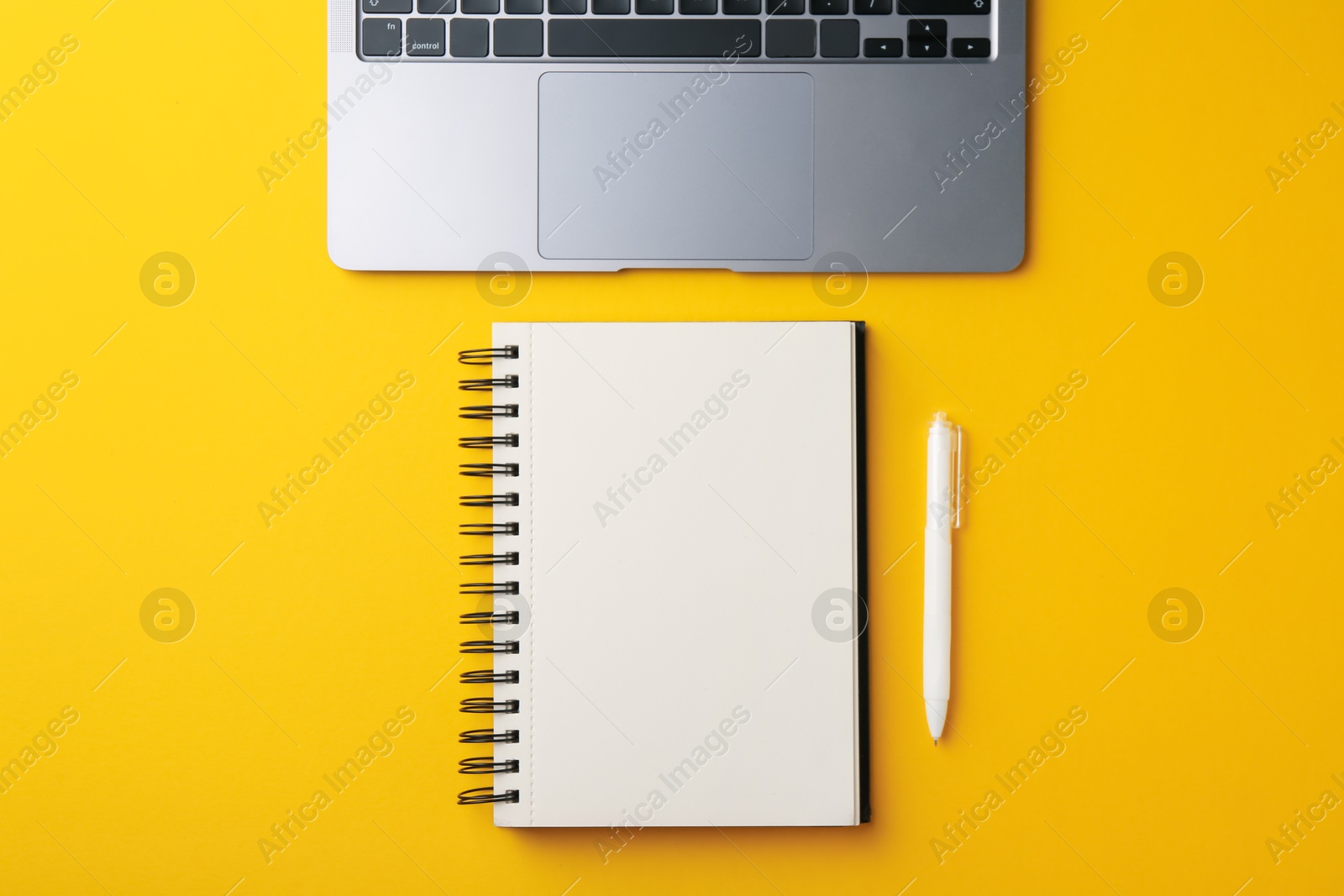 Notebook, pen and laptop on yellow background, flat lay Photo of Notebook, pen and laptop on yellow background, flat lay