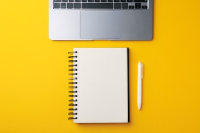 Photo of Notebook, pen and laptop on yellow background, flat lay