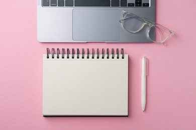 Photo of Notebook, pen, glasses and laptop on pink background, flat lay