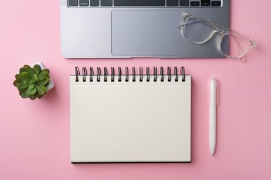 Photo of Notebook, pen, glasses, laptop and floral decor on pink background, flat lay