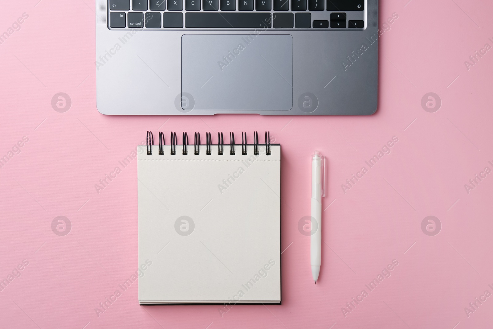 Photo of Notebook, pen and laptop on pink background, flat lay
