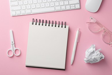 Photo of Notebook, other stationery, glasses, computer keyboard and mouse on pink background, flat lay