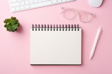 Photo of Notebook, pen, glasses, floral decor, computer keyboard and mouse on pink background, flat lay