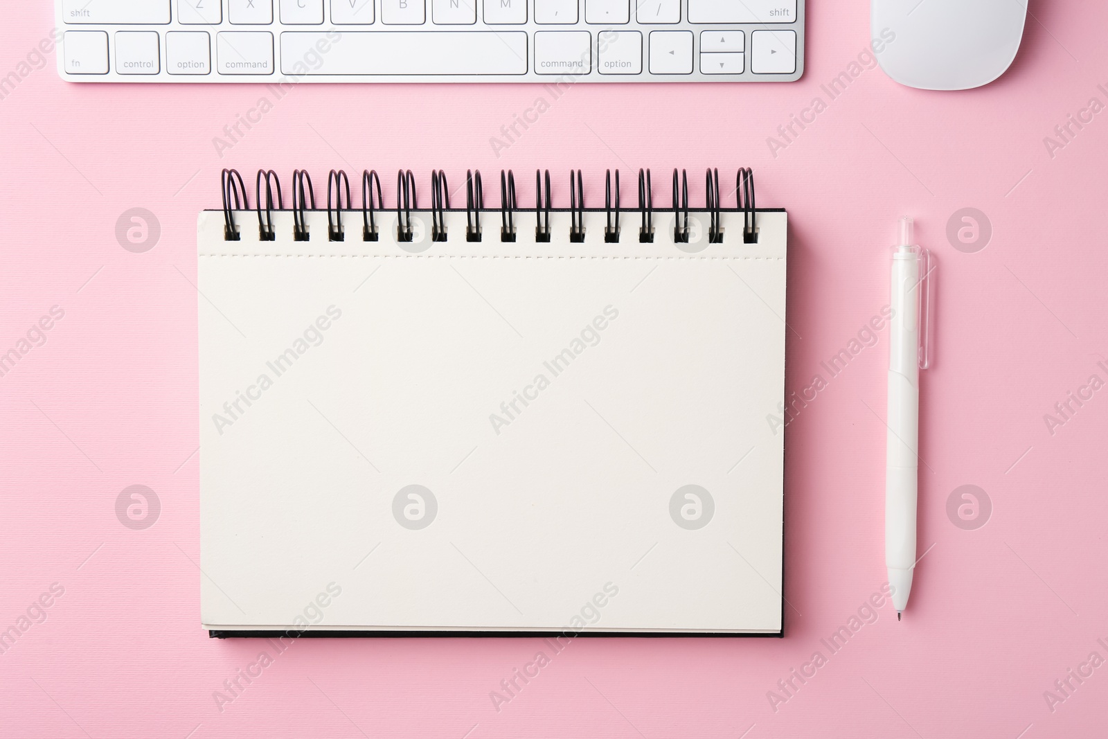 Notebook, pen, computer keyboard and mouse on pink background, flat lay Photo of Notebook, pen, computer keyboard and mouse on pink background, flat lay