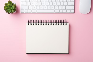 Photo of Notebook, floral decor, computer keyboard and mouse on pink background, flat lay