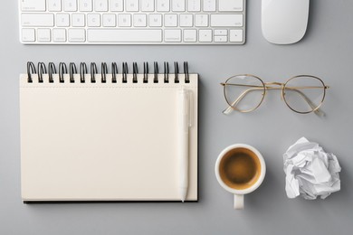 Photo of Notebook, pen, crumpled paper, coffee, computer keyboard and mouse on grey background, flat lay