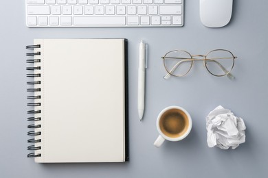 Photo of Notebook, pen, crumpled paper, coffee, computer keyboard and mouse on grey background, flat lay