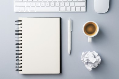 Photo of Notebook, pen, crumpled paper, coffee, computer keyboard and mouse on grey background, flat lay