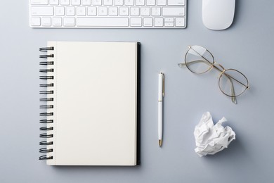 Photo of Notebook, pen, crumpled paper, computer keyboard and mouse on grey background, flat lay