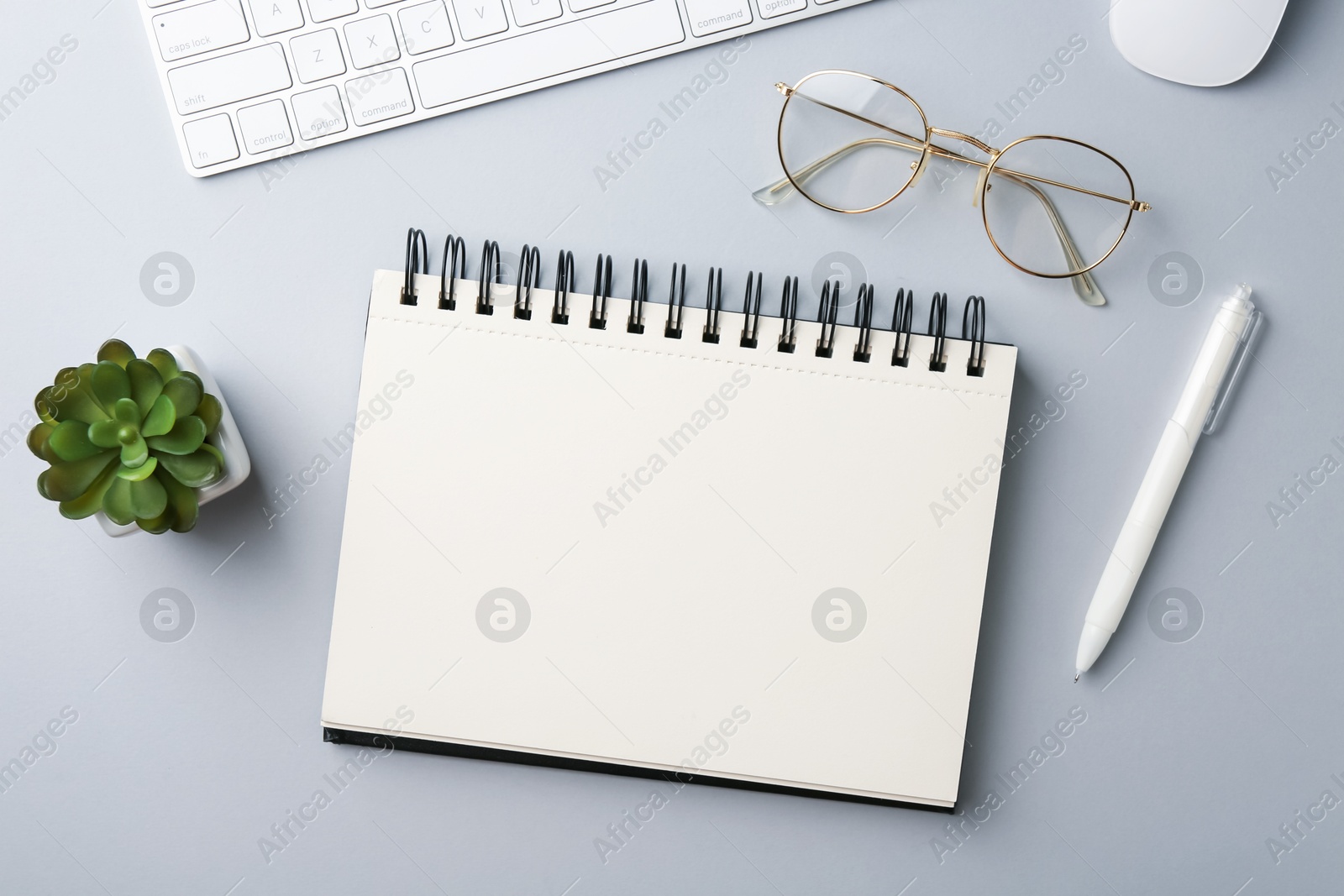 Notebook, pen, glasses, computer keyboard, mouse and floral decor on grey background, flat lay Photo of Notebook, pen, glasses, computer keyboard, mouse and floral decor on grey background, flat lay