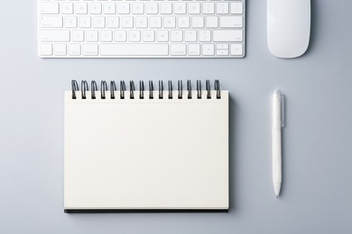 Photo of Notebook, pen, computer keyboard and mouse on grey background, flat lay