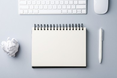 Photo of Notebook, pen, crumpled paper, computer keyboard and mouse on grey background, flat lay