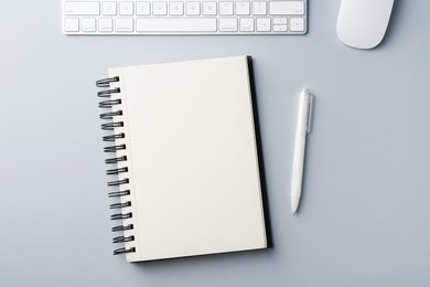 Photo of Notebook, pen, computer keyboard and mouse on grey background, flat lay