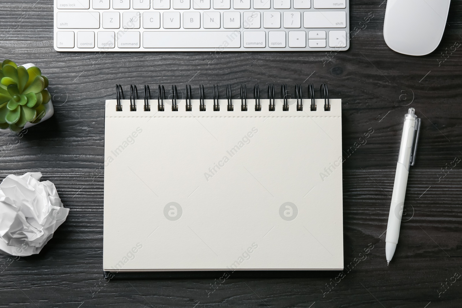 Photo of Notebook, pen, crumpled paper, floral decor, computer keyboard and mouse on black wooden table, flat lay