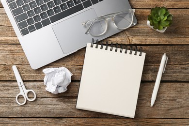 Photo of Notebook, other stationery, glasses, floral decor and laptop on wooden table, flat lay