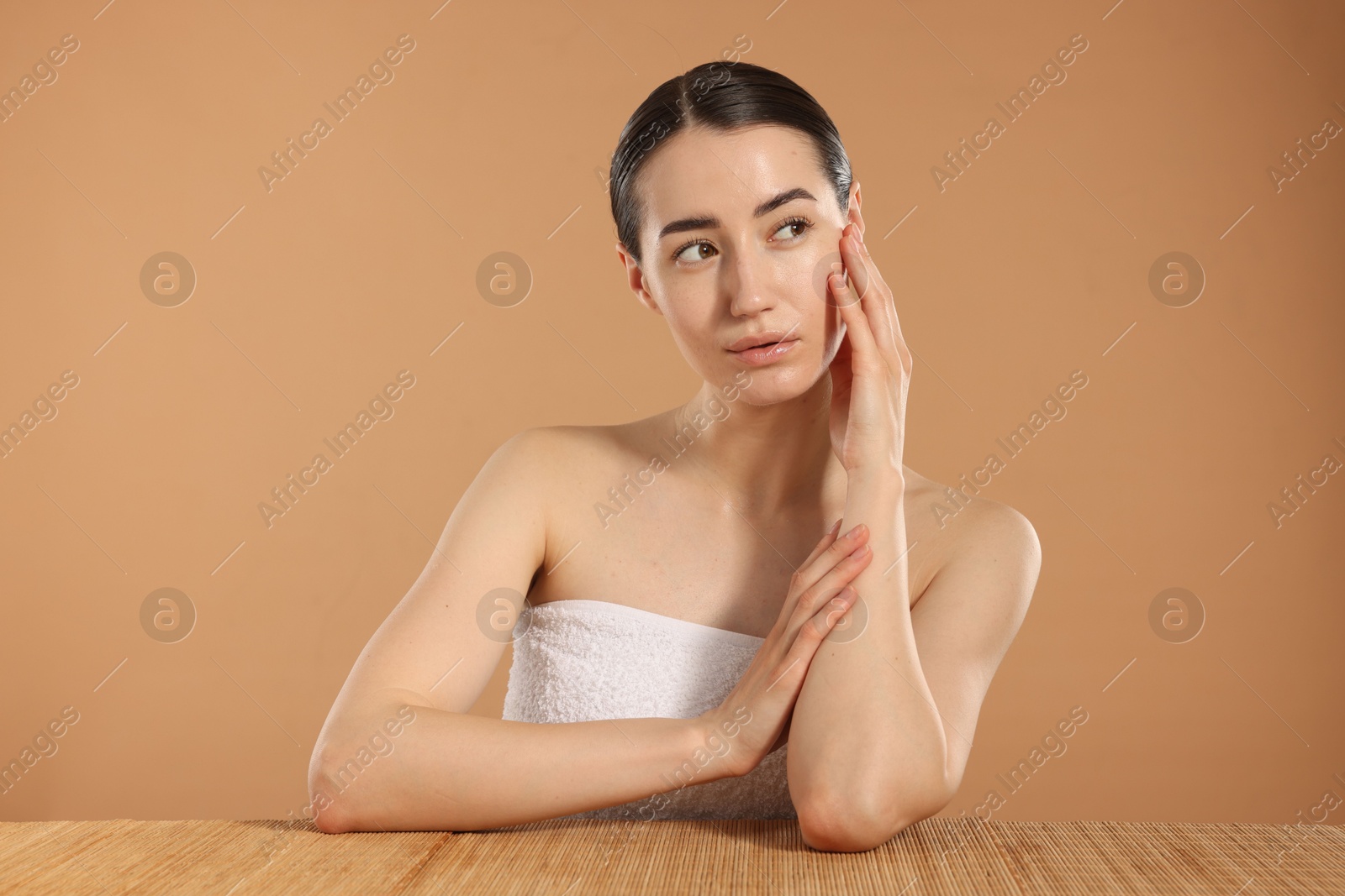 Beautiful woman after spa treatment at bamboo table on beige background Photo of Beautiful woman after spa treatment at bamboo table on beige background