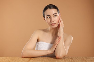 Photo of Beautiful woman after spa treatment at bamboo table on beige background
