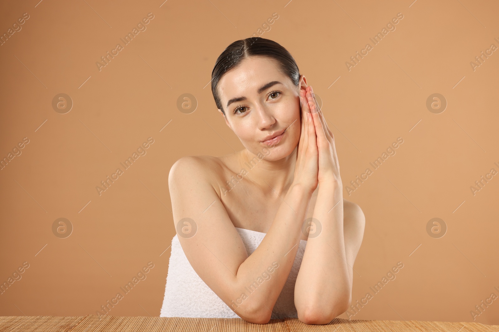 Beautiful woman after spa treatment at bamboo table on beige background Photo of Beautiful woman after spa treatment at bamboo table on beige background