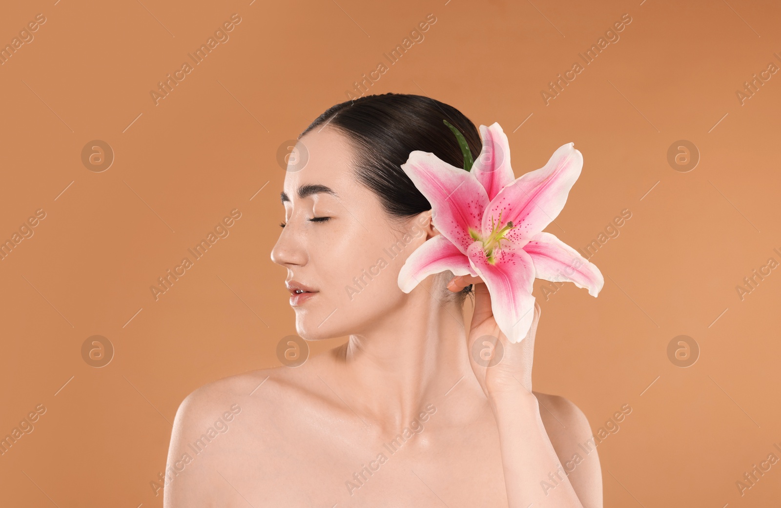 Beautiful woman after spa treatment with lily flower on beige background Photo of Beautiful woman after spa treatment with lily flower on beige background