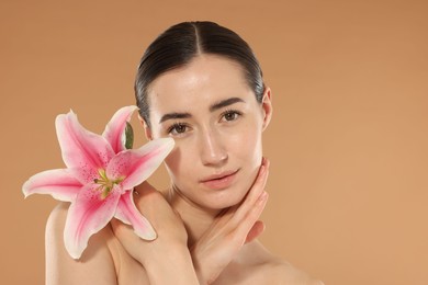 Photo of Portrait of beautiful woman after spa treatment with lily flower on beige background