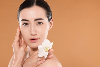 Photo of Beautiful woman after spa treatment with orchid flower on beige background, closeup. Space for text
