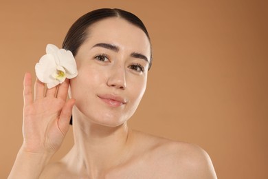 Photo of Beautiful woman after spa treatment with orchid flower on beige background, closeup